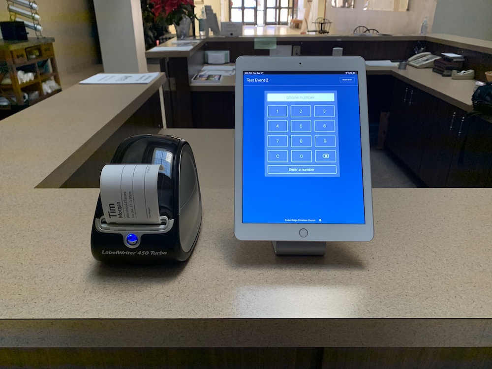 Dymo printer next to iPad running Planning Center Check-Ins